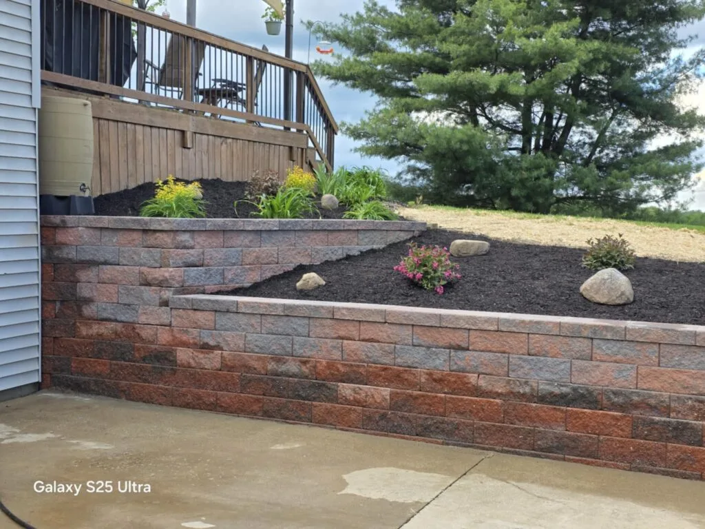 A multi-tiered retaining wall with dead ornamental grass on a cloudy day.