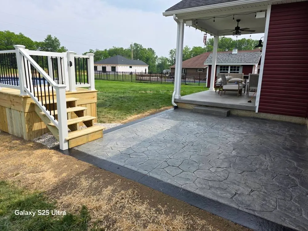 View of a concrete patio with a stone pattern, an outdoor deck, and a covered porch with outdoor seating.